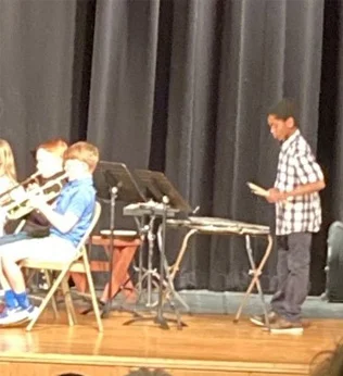 Sudan playing percussions in a school band on stage