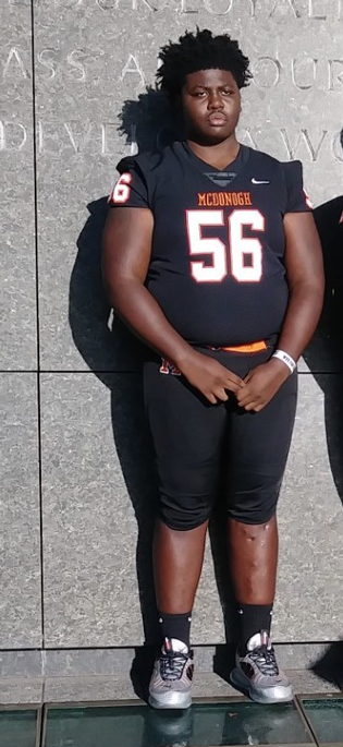 Tamarus standing with straight legs in his football uniform