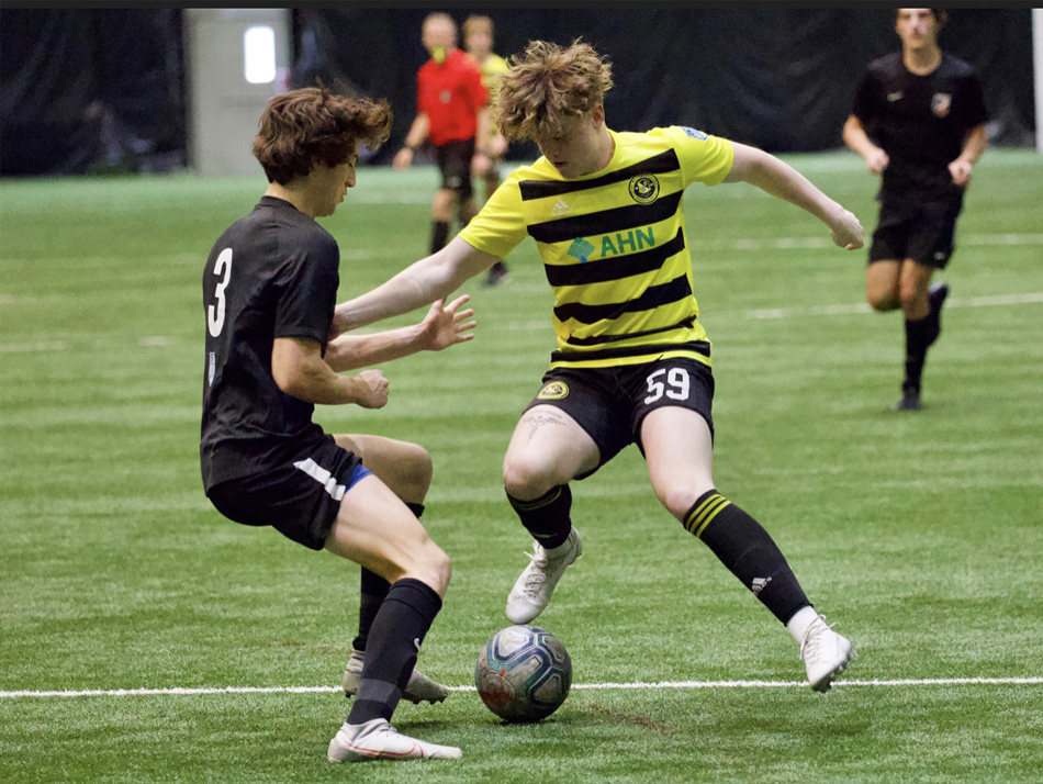 Thomas in uniform playing soccer with an opponent