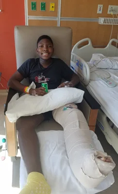 Zuri sitting next to his hospital bed with his leg bandaged after surgery