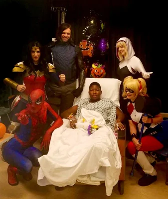 Zuri in a wheelchair surrounded by superhero characters at a party at the Children's Hospital