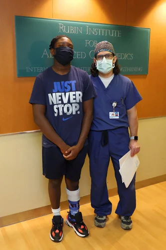 Zuri after a follow-up appointment standing with Dr. McClure by the International Center for Limb Lengthening sign