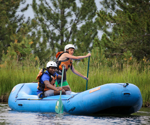 Zuri paddling a raft outdoors with another boy