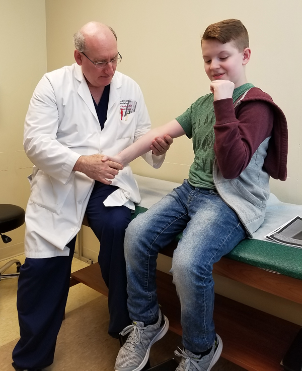Dr. Herzenberg checking Aaron's arm in clinic