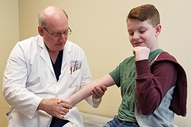 Dr. Herzenberg checking Aaron’s arm in clinic