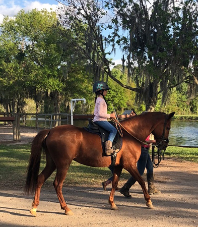 Emma horseback riding on a brown horse