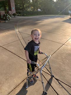 Jackson as a young boy smiling using his walker