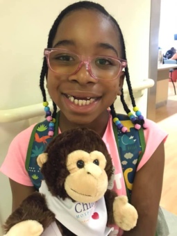 Kennedee with a stuffed animal monkey given from Sinai's Children's Hospital