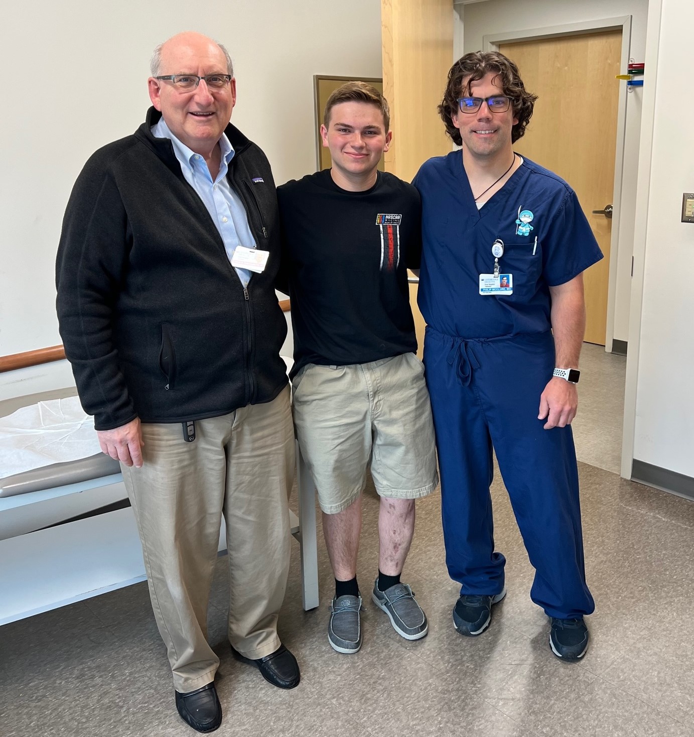 Matthew as a young adult standing between Dr. John Herzenberg and Dr. Philip McClure