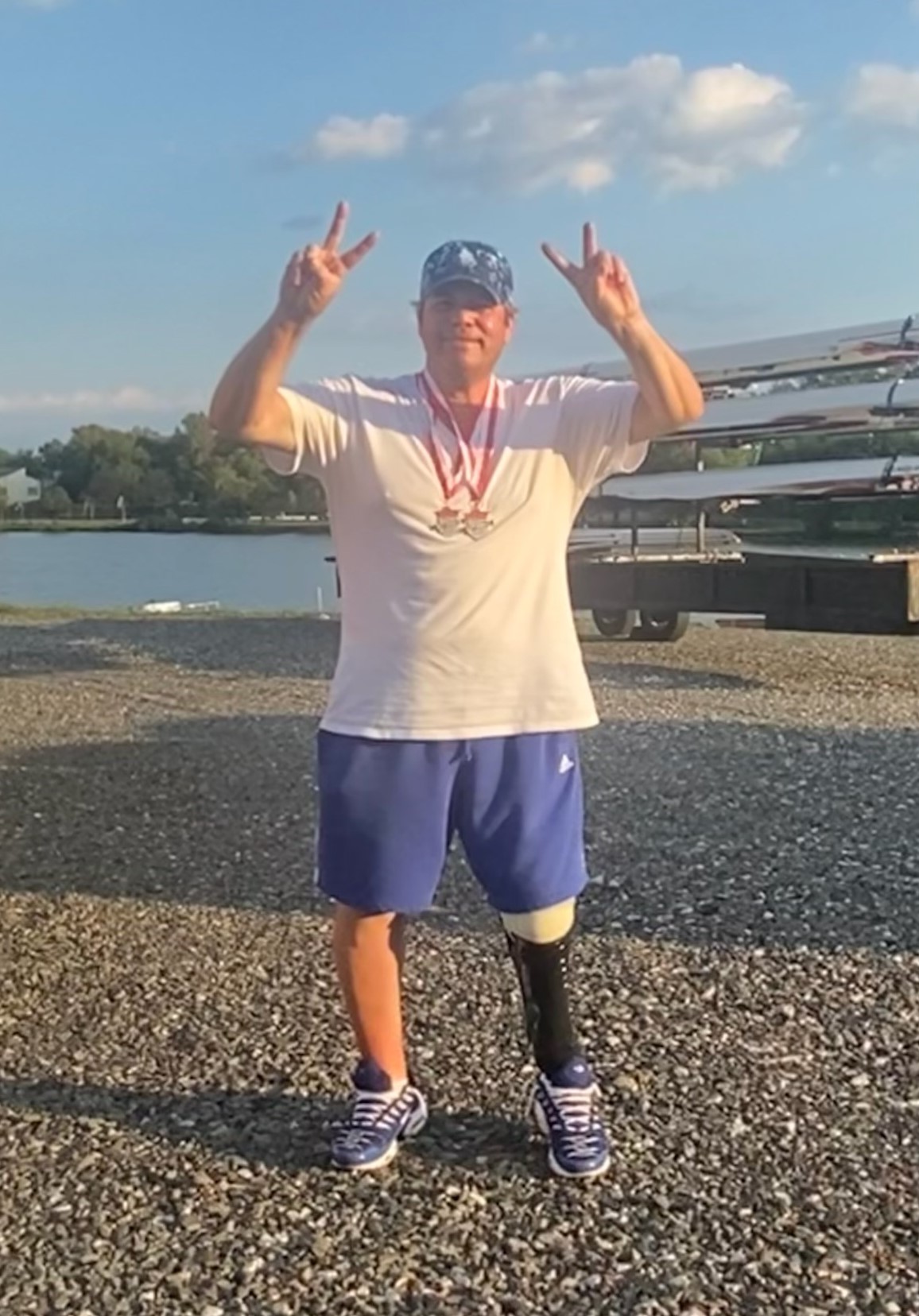  Ronnie standing wearing his medals from the regatta he won making the victory sign with both hands