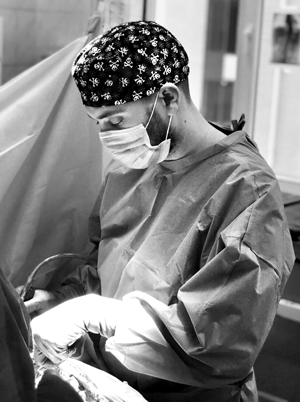 Dr. Valentyn Rohozynskyi in scrubs performing surgery in an operating room